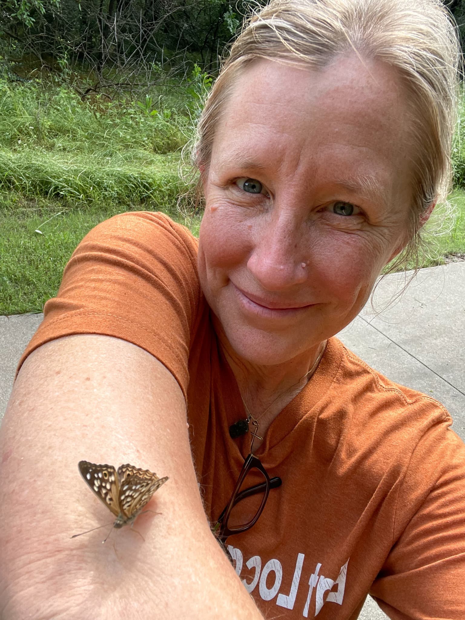 A butterfly resting on Heather’s arm outdoors
