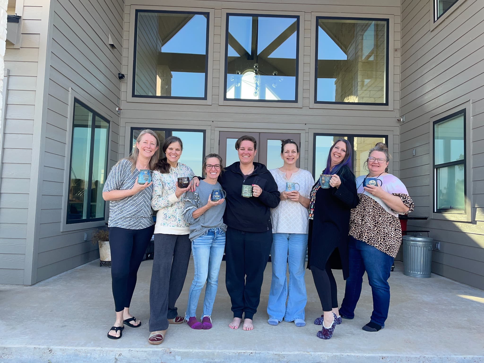 Heather and SHINE participants outdoors holding handmade mugs